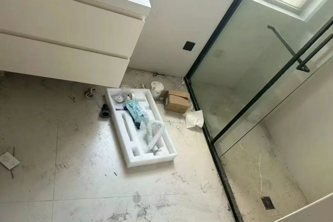 卫浴空间保洁清洁前：卫浴地面有包装材料、碎屑和积灰，边角需要清理。